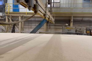 MDF press line with Canguard mat spray applying coating to fiberboard for improved heat transfer and surface quality
